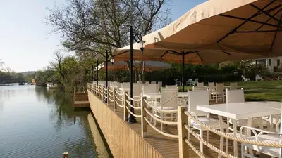 a restaurant with white tables and chairs next to a river at The Escape Hotel in Agva