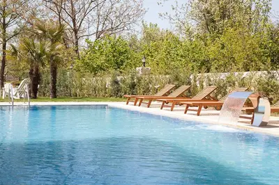 a swimming pool with wooden benches and a group at The Escape Hotel in Agva