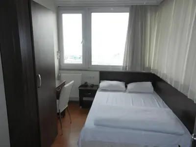 a bedroom with a bed and a desk and two windows at Cagri Hotel in Istanbul