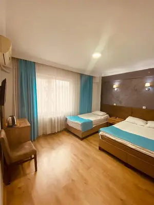 a hotel room with two beds and a chair at Malkoç Hotel in Istanbul