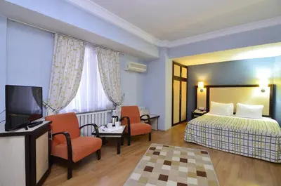 a hotel room with a bed and chairs and a television at Grand Gebze Hotel in Gebze