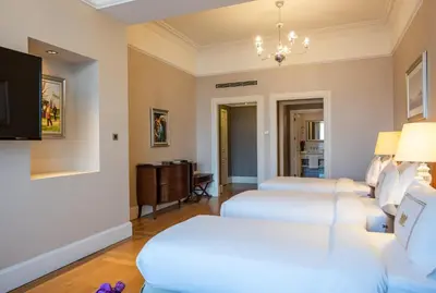 a living room with two white beds and a tv at Pera Palace Hotel in Istanbul