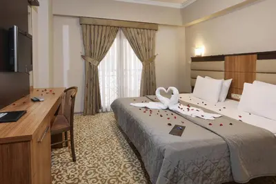 a hotel room with a bed and a desk and a television at New Balturk Hotel Izmit in Kocaeli