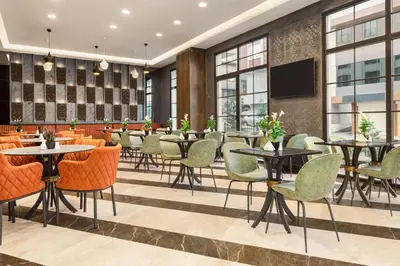 a restaurant with tables and chairs and a flat screen tv at Ramada Encore By Wyndham Istanbul Basin Express in Istanbul