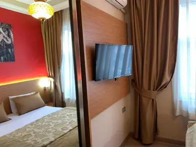 a room with a bed and a television on a wall at Antique Hostel in Istanbul