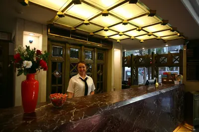 a man standing behind a bar with a vase of flowers at Istanbul Royal Hotel in Istanbul