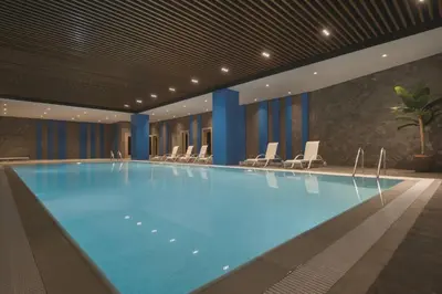 a large swimming pool in a hotel with chairs at TRYP by Wyndham Istanbul Basın Ekspres in Istanbul