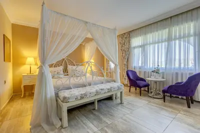 a bedroom with a canopy bed and two purple chairs at Agva Greenline Guesthouse (Adult Only +12) in Agva