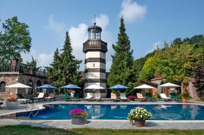 a swimming pool with a lighthouse in the background at Wineport Lodge Agva Riverside Hotel & Winery in Agva
