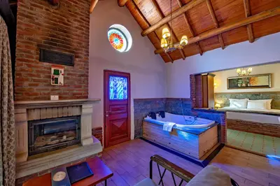 a room with a tub and a bed and a fireplace at Wineport Lodge Agva Riverside Hotel & Winery in Agva