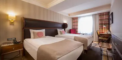 a hotel room with two beds and a desk at Titanic Comfort Sisli in Istanbul