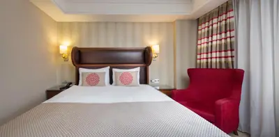 a bedroom with a bed and a red chair at Titanic Comfort Sisli in Istanbul