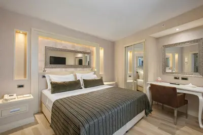 a bedroom with a bed and a desk and a mirror at Limak Eurasia Luxury Hotel in Istanbul