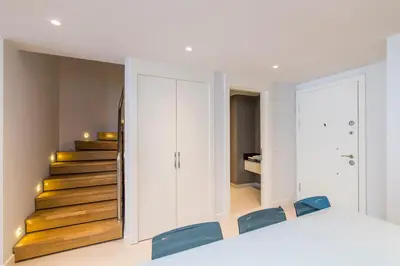 a room with a staircase with white cabinets and blue chairs at Classy Suite Taksim in Istanbul