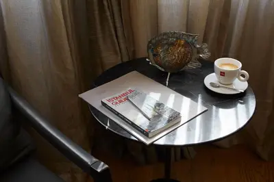 a glass table with a book and a cup of coffee at Taksim Prelude Hotel in Istanbul