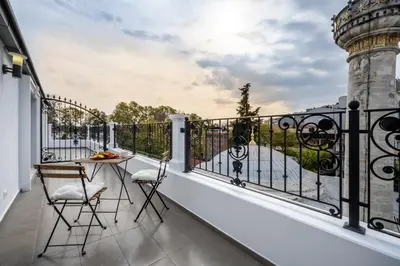 a balcony with a table and chairs and a lighthouse at Çırağan Apart Bosphorus in Istanbul