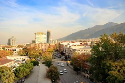 a city with cars driving down a street with buildings at Burcman Hotel in Bursa