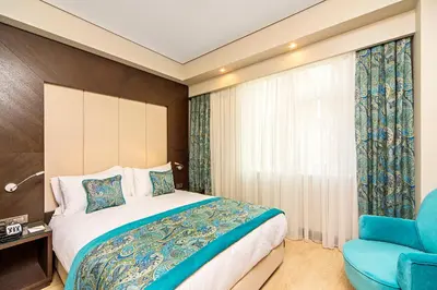 a bedroom with a bed and a blue chair at Mukarnas Taksim Hotel in Istanbul