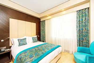 a bedroom with a bed and a blue chair at Mukarnas Taksim Hotel in Istanbul
