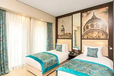 a hotel room with two beds and a painting on the wall at Mukarnas Taksim Hotel in Istanbul