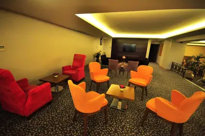 a waiting room with orange chairs and tables at Hotel Osaka Airport in Istanbul