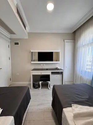 a bedroom with two beds and a desk with a television at Ens Hotel in Istanbul