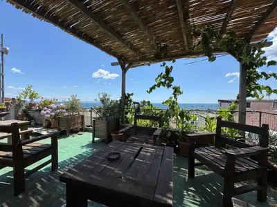 a patio with a wooden table and benches and the ocean at Gedikpasa Konagi Hotel in Istanbul