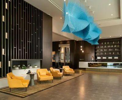 a lobby with yellow chairs and a blue sculpture at WestSide Residences by Rotana in Istanbul
