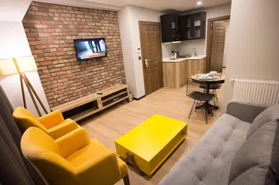 a living room with a couch and yellow chairs and a kitchen at Long Stay İstanbul Residence in Istanbul