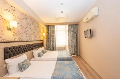 a hotel room with two beds and a tv at Tugra Hotel in Istanbul