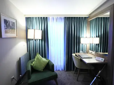 a hotel room with a desk and a green chair at ibis Styles Istanbul Bomonti in Istanbul