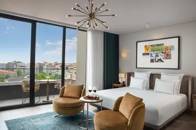 a bedroom with a bed and two chairs and a large window at Glens Palas Istanbul Nisantasi in Istanbul