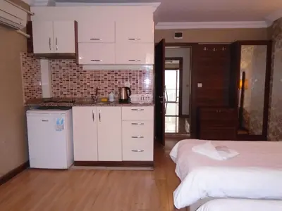 a room with two beds and a kitchen with white cabinets at City House in Istanbul