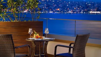 a table with two chairs and wine glasses on a balcony at Port Bosphorus Hotel in Istanbul