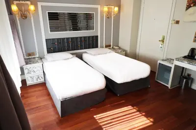 two beds in a room with wood floors and a window at Bakirkoy Tashan Business & Airport Hotel in Istanbul