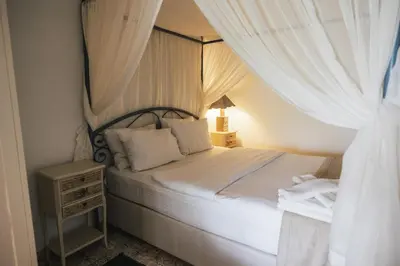 a bedroom with a canopy bed with white curtains at Park Mandalin Hotel - Adult only in Agva