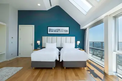 two beds in a bedroom with blue walls and windows at Radisson Residences Avrupa TEM Istanbul in Istanbul