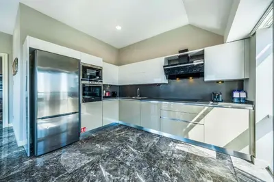 a kitchen with white cabinets and a stainless steel refrigerator at Radisson Residences Avrupa TEM Istanbul in Istanbul