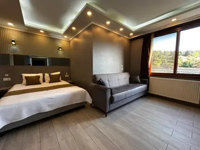 a bedroom with a bed and a couch and a window at Sahrakent Otel Ataşehir in Istanbul