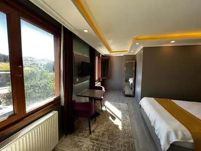 a hotel room with a bed and a desk and window at Sahrakent Otel Ataşehir in Istanbul