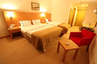 a hotel room with two beds and a red chair at Shilla Hotel in Velimeşe