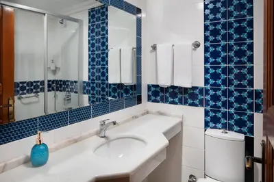 a bathroom with a sink and a toilet and blue tiles at Hotel Sari Konak in Istanbul