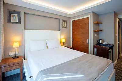 a bedroom with a large white bed and two lamps at Aston Hotel Taksim in Istanbul