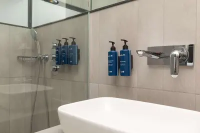 a bathroom with a shower with blue bottles on the wall at Radisson Blu Hotel Istanbul Asia in Istanbul