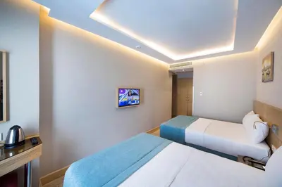 a hotel room with two beds and a tv at Meretto Hotel LALELİ in Istanbul