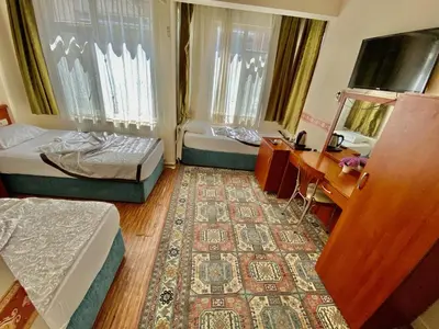 a room with two beds and a desk and a rug at Kadikoy Kervansaray Hotel in Istanbul