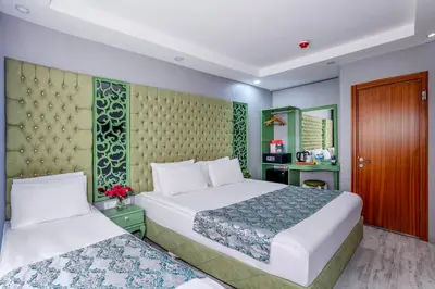 a hotel room with two beds and a cabinet at Green Garden Hotel - Bahçelievler in Istanbul