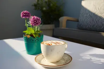 a cup of coffee on a table with a vase with flowers at Albatros Hagia Sophia Hotel in Istanbul