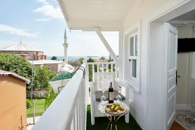 a white balcony with a table with a bottle of wine and fruit on it at Mataraci Konak in Istanbul