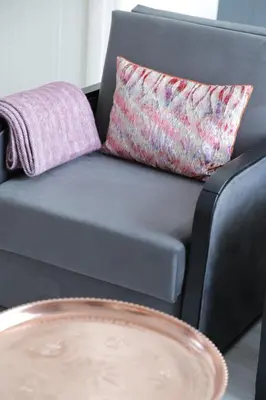 a gray couch with a pillow and a table at Bayer Hotel in Istanbul